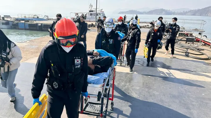Gerettete Besatzungsmitglieder werden von Rettungskräften auf Bahren getragen, als sie in einem Hafen in Mokpo in Südkorae ankommen. (Foto: Uncredited/YONHAP/AP/dpa)