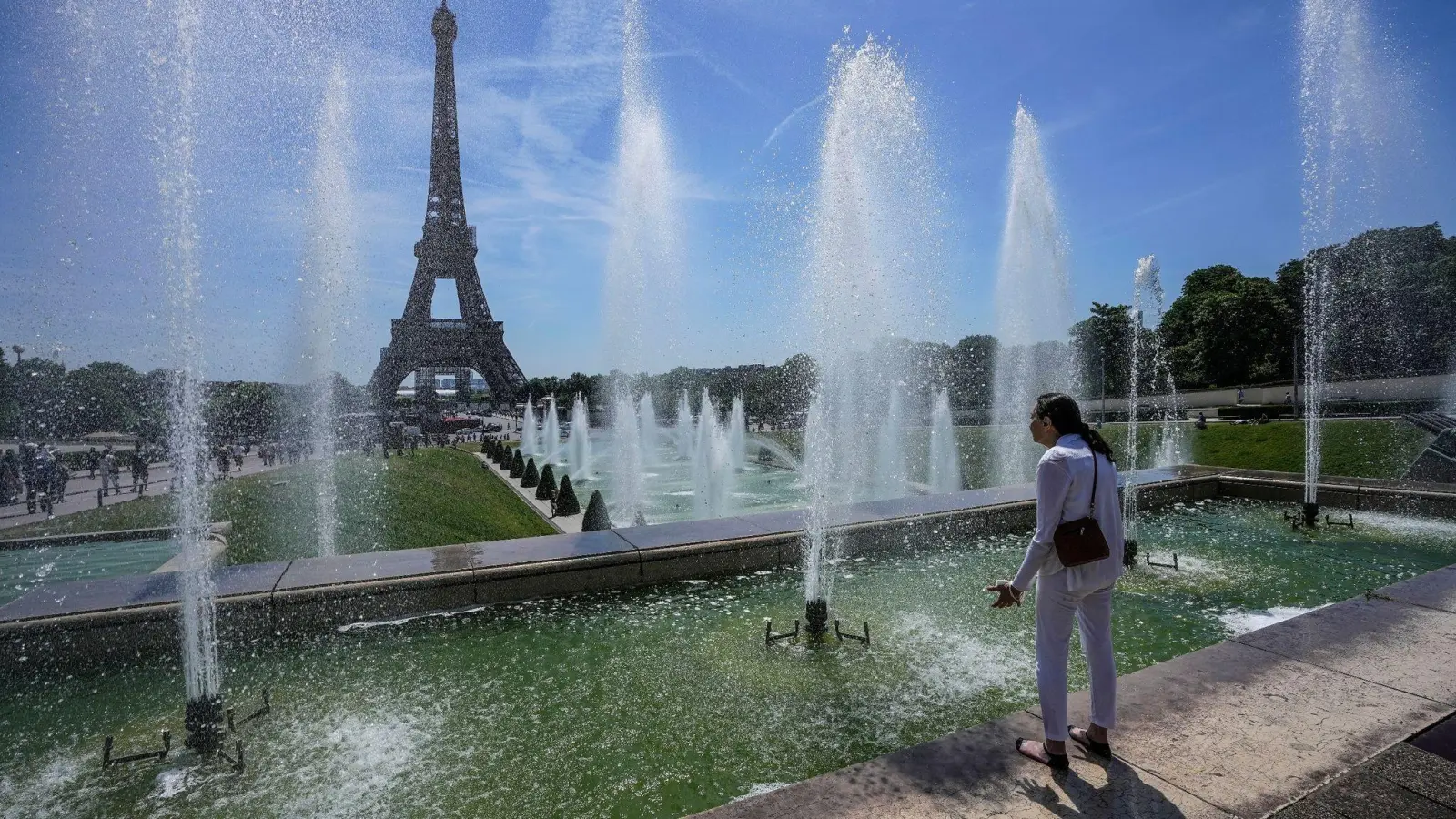Eine Frau kühlt sich an einem Brunnen in der Nähe des Eiffelturms ab. Wichtige Faktoren für die Zunahme von Hitzewellen insbesondere in Westeuropa sind aus Sicht von Potsdamer Forschern Veränderungen des sogenannten Jetstreams. (Foto: Michel Euler/AP/dpa)