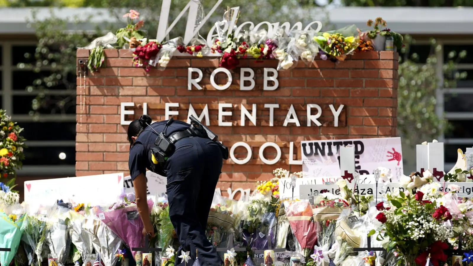 Eine Polizistin legt Blumen vor der Robb Elementary School in Texas nieder. Bei einem Schulmassaker hatte ein Schütze Ende Mai 19 Kinder und zwei Lehrerinnen erschossen. (Foto: Wu Xiaoling/XinHua/dpa)