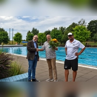 Bürgermeister Dr. Ulrich Grünwald (links) und Betriebsleiter Heiko Hercher (rechts) gratulierten Stammgast Wolfgang Kullmann mit einem Blumenstrauß und einem Gutschein für eine Saisonkarte. Marlies Kullmann war bei dem Termin verhindert. (Foto: Stadt Feuchtwangen/Rebecca Weber)