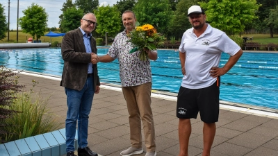 Bürgermeister Dr. Ulrich Grünwald (links) und Betriebsleiter Heiko Hercher (rechts) gratulierten Stammgast Wolfgang Kullmann mit einem Blumenstrauß und einem Gutschein für eine Saisonkarte. Marlies Kullmann war bei dem Termin verhindert. (Foto: Stadt Feuchtwangen/Rebecca Weber)