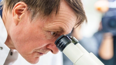 Karl Lauterbach (SPD), Bundesgesundheitsminister, betrachtet unter einem Mikroskop Krebszellen. (Foto: Andreas Arnold/dpa)