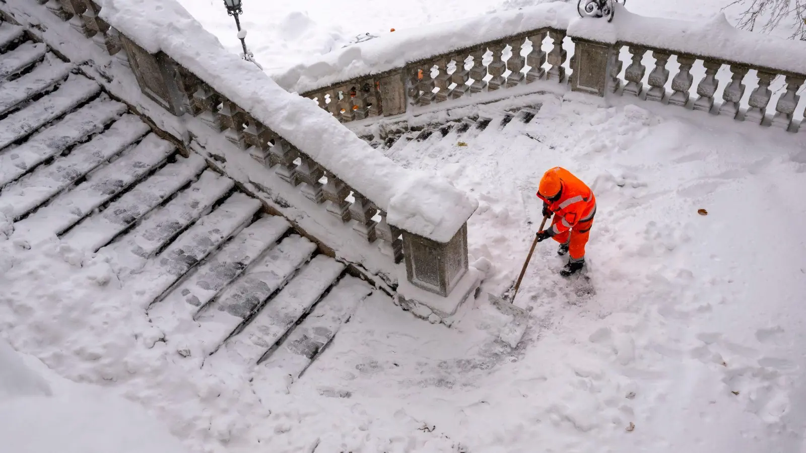 Ein Mitarbeiter der Münchner Stadtreinigung schippt am Friedensengel Schnee von der Freitreppe. (Foto: Peter Kneffel/dpa)