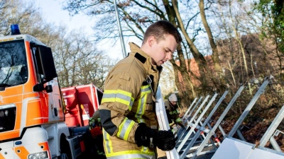 Einsatzkräfte der Feuerwehr bauen ein mobiles Deichsystem ab. (Foto: Hauke-Christian Dittrich/dpa)