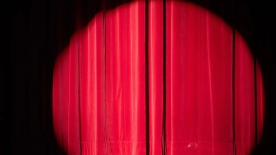 Ein Scheinwerfer erhellt den Vorhang auf einer Bühne. (Foto: Sebastian Kahnert/dpa/Symbolbild)
