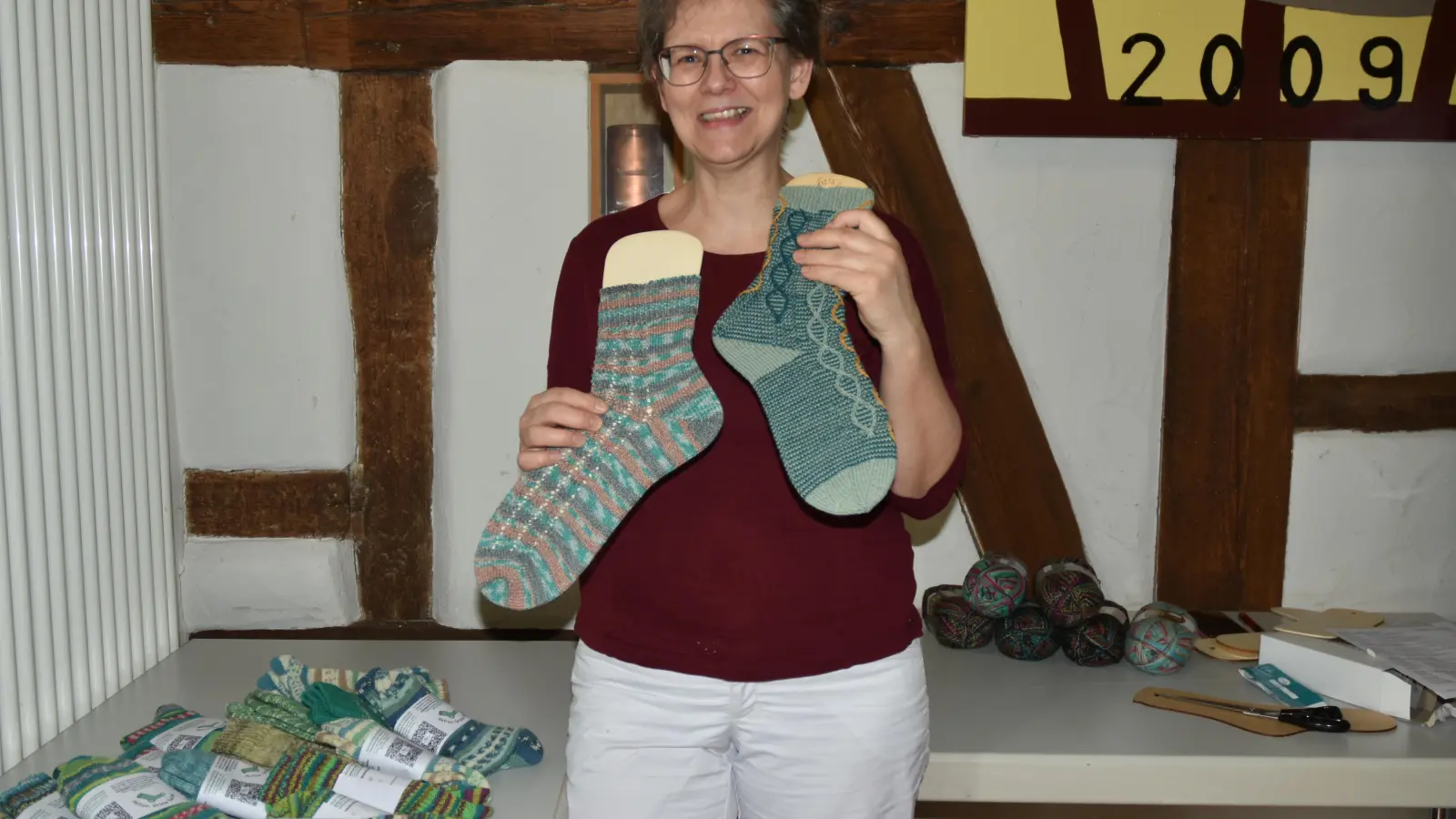 Gruppenleiterin Heike Madiar zeigt grüne Socken. Das linke Exemplar hat eine Zunahmeferse, die rechte eine Bumerangferse. (Foto: Anita Dlugoß)