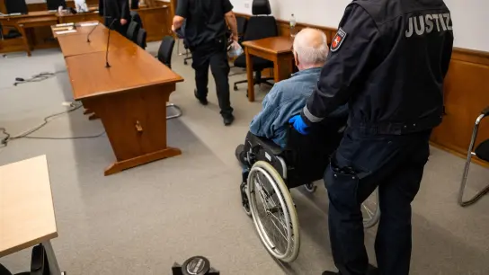 Der Angeklagte wird im Rollstuhl in den Saal des Landgerichts geschoben. (Foto: Philipp Schulze/dpa)