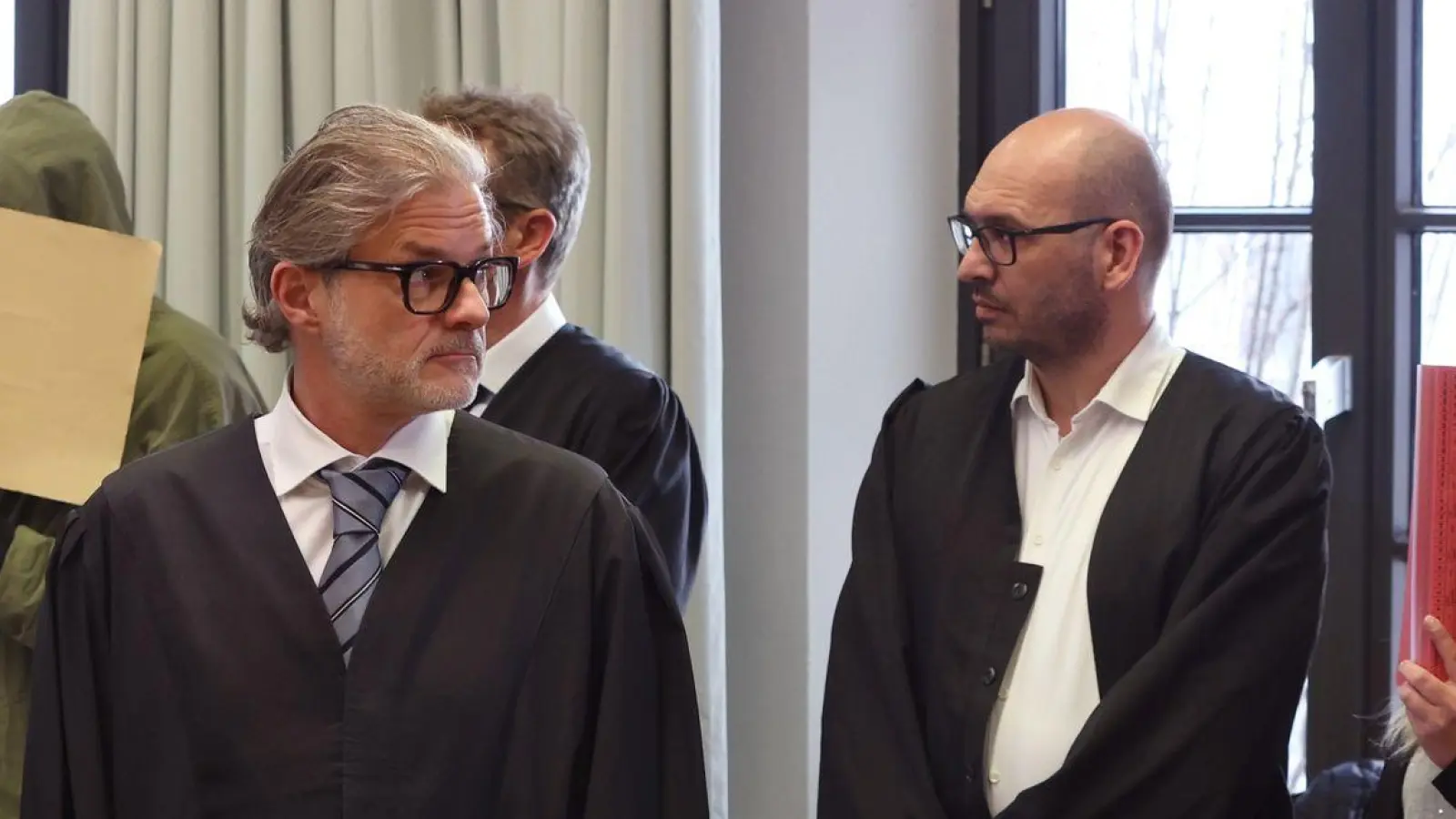 Ein wegen Doppelmordes angeklagter Mann (2.v.l) und seine ebenfalls angeklagte Frau (r), stehen hinter einem der Beihilfe angeklagten Mann (l), in der Anklagebank im Landgericht. (Foto: Karl-Josef Hildenbrand/dpa)