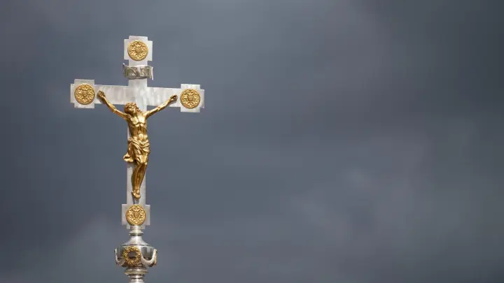 Ein katholisches Kruzifix ist vor dunklen Wolken zu sehen. (Foto: Marijan Murat/dpa/Symbolbild)
