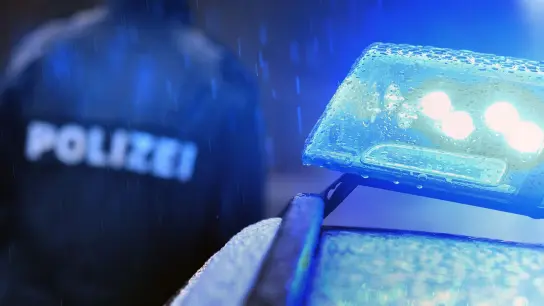 Ein Polizist steht vor einem Streifenwagen dessen Blaulicht aktiviert ist. (Foto: Karl-Josef Hildenbrand/dpa/Symbolbild)