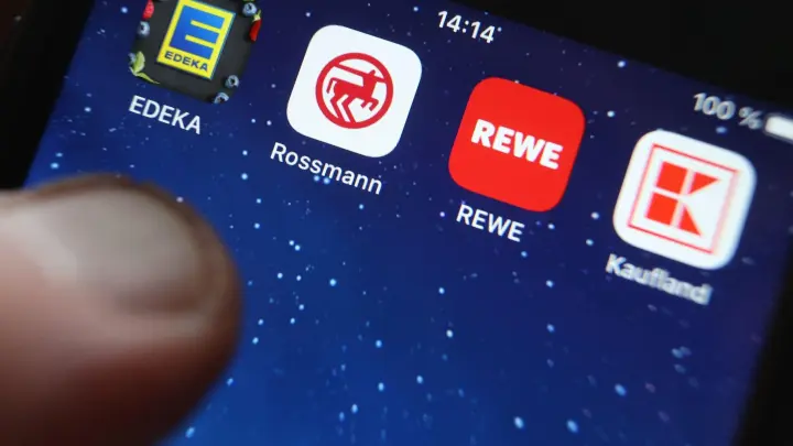 Icons der Apps von den Handelsketten wie Edeka, Rossmann und REWE auf dem Display eines iPhones. (Foto: Karl-Josef Hildenbrand/dpa)