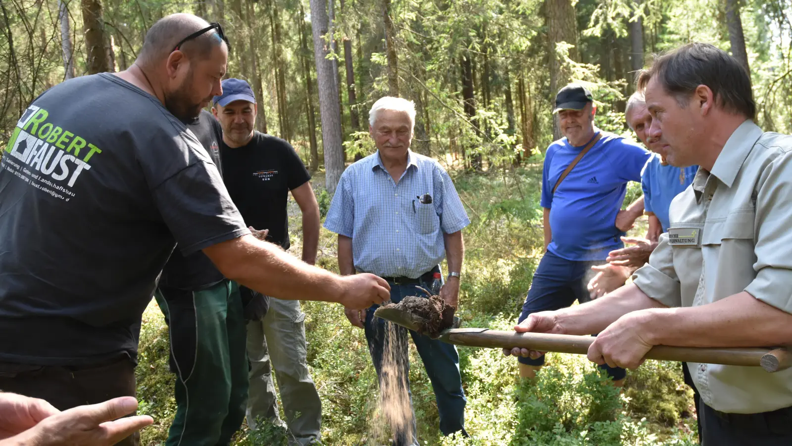 An Stellen innerhalb und außerhalb der Lichtung ließ Förster Gernot Käßer (rechts) die Waldbauern den Boden fühlen. Zuerst wurde eine staubtrockene Probe außerhalb vorgeführt. (Foto: Anita Dlugoß)