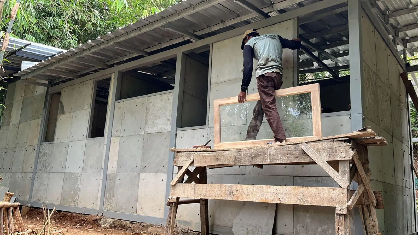 Ein Mann arbeitet am Rohbau eines einfachen Hauses, bei dem gebrauchte Windeln einen Teil des Baumaterials ersetzen. (Foto: Anjar Primasetra/Springer Nature/dpa)