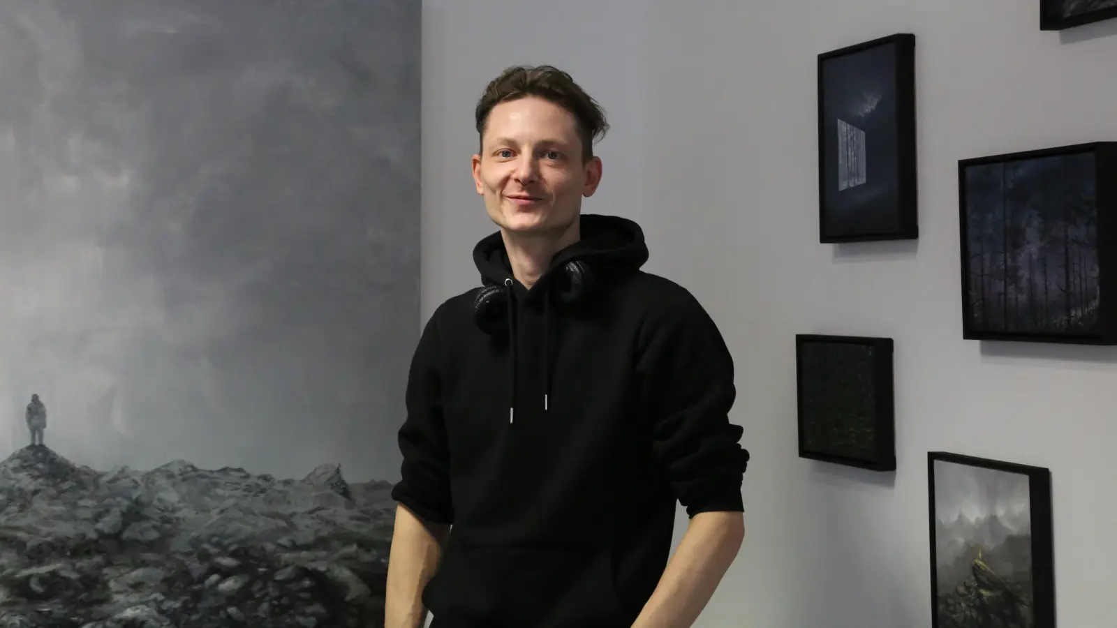 Der Maler Jan Gemeinhardt inmitten seiner stillen, weiten, oft düsteren und geheimnisvollen Landschaften: In der Ausstellung in Heilsbronn sind viele Entdeckungen möglich. (Foto: Martina Kramer)
