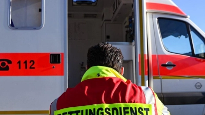 „Rettungsdienst“ steht auf der Jacke eines Mannes vor einem Rettungswagen der Feuerwehr. (Foto: Jens Kalaene/dpa/Symbolbild)