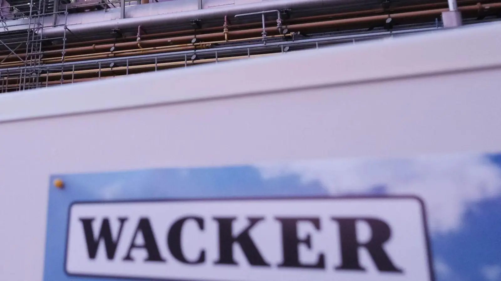 Eine Schautafel mit der Aufschrift „Wacker“ steht vor einer Anlage auf dem Gelände der Wacker Chemie Nünchritz. (Foto: Sebastian Willnow/dpa)
