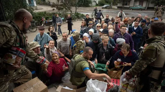 Ukrainische Soldaten verteilen Lebensmittel an an die Einwohner von Isjum. (Foto: Evgeniy Maloletka/AP/dpa)