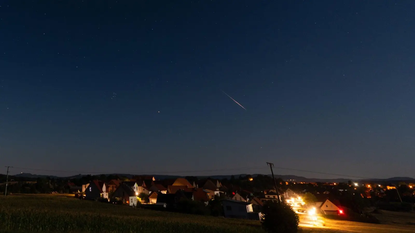 Eine Sternschnuppe verglüht am Nachthimmel über Höfen in Bayern. (Foto: Nicolas Armer/dpa)