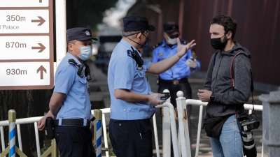 Ein ausländischer Journalist wird in Peking von Polizisten angehalten und befragt, nachdem er versucht hatte, die Busse von Delegierten des chinesischen Volkskongresses zu fotografieren (Archivbild). (Foto: Andy Wong/AP/dpa)