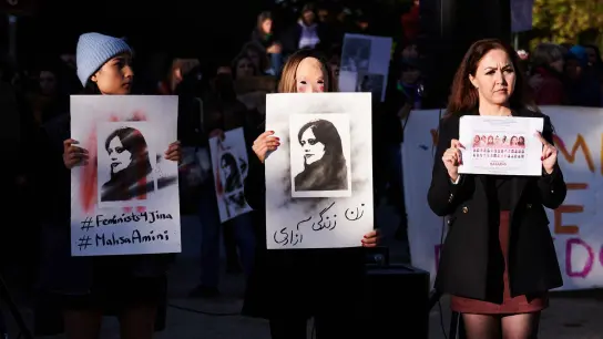 Demonstrantinnen halten in Berlin Schilder in die Höhe, auf der die im Iran getötete Kurdin Jina Mahsa Amini zu sehen ist. (Foto: Annette Riedl/dpa)