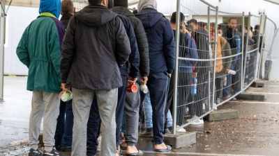 Flüchtlinge warten in einer Landeserstaufnahmestelle in einer Schlange. Der Landkreistag spricht sich für die Prüfung von Asylanträgen an den EU-Außengrenzen und die Beendigung freiwilliger Aufnahmeprogramme aus. (Foto: Stefan Puchner/dpa)