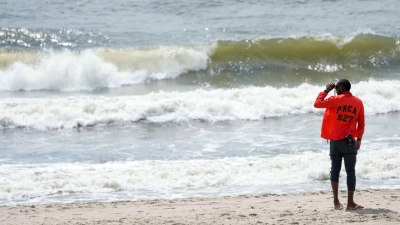 Ein Mitarbeiter des „New York City Department of Parks and Recreation“ patrouilliert mit einem Fernglas am Strand von Rockaway. Eine 50-jährige Frau ist beim Baden nahe der Millionenmetropole von einem Hai schwer verletzt worden. (Foto: Mary Altaffer/AP/dpa)