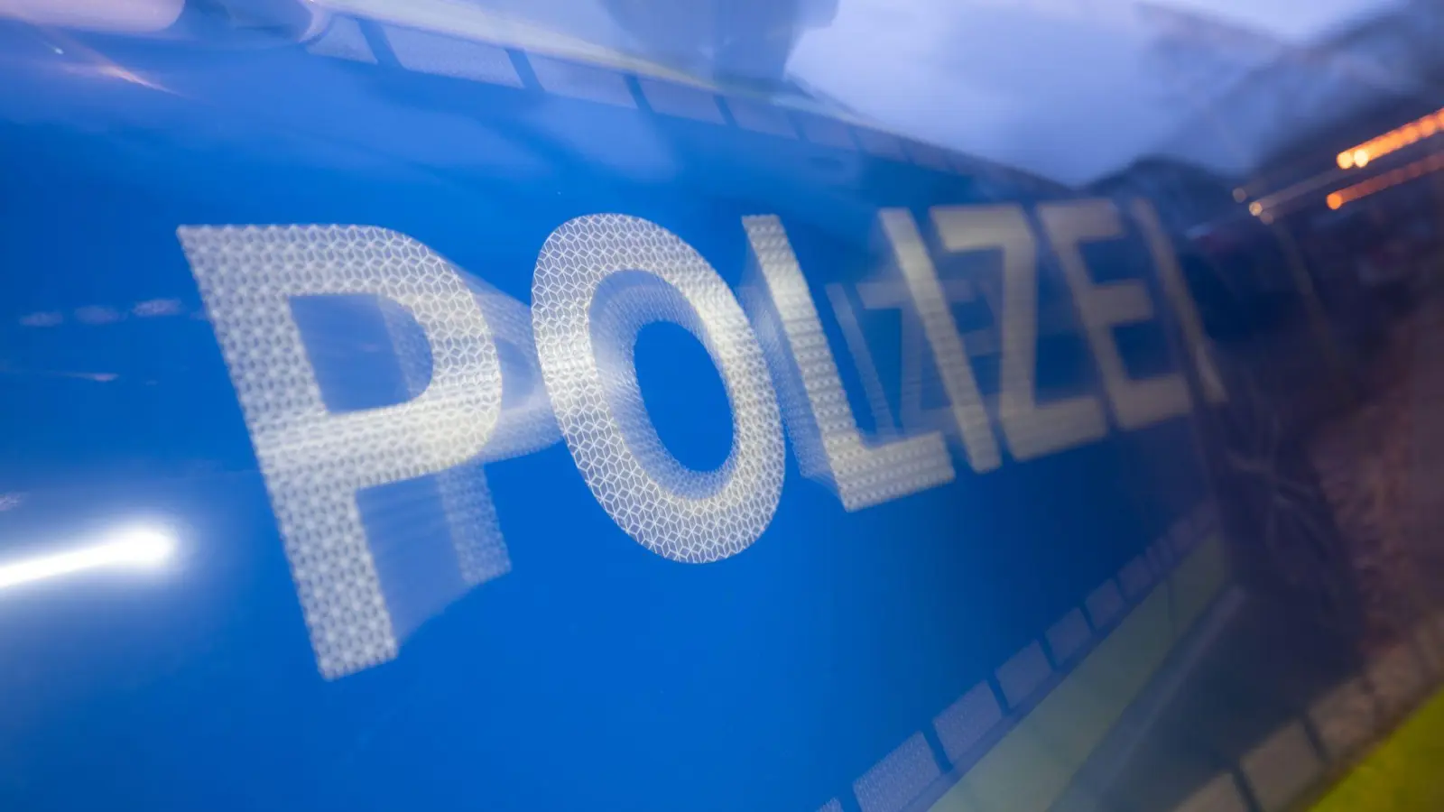 Das Wort Polizei ist im Rahmen eines Fototermins auf der Karosserie eines Polizeifahrzeugs zu sehen (gestellte Szene, Wischeffekt durch Langzeit). (zu dpa: «Polizei warnt: Minderwertiger Asphalt und rüde Erpressung») (Foto: Marijan Murat)