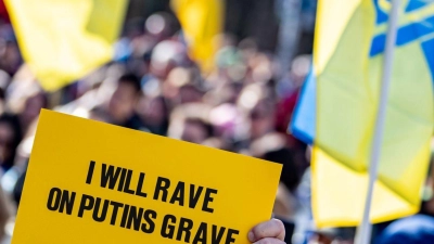 Eine Person hält auf der Solidaritätsdemonstration des Vereins Vitsche „Zusammen Demokratie verteidigen“ ein Schild mit der Aufschrift „I will rave on Putins grave“ teil. (Foto: Fabian Sommer/dpa)