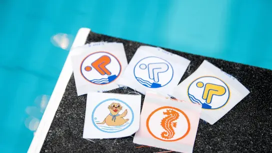 Schwimmabzeichen liegen in einem Schwimmbad auf einem Startblock. (Foto: Matthias Balk/dpa/Symbolbild)