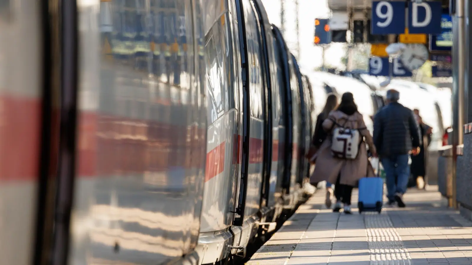Reisende gehen mit Gepäck am Bahnsteig am Nürnberger Hauptbahnhof neben einem ICE entlang. (Foto: Daniel Karmann/dpa)