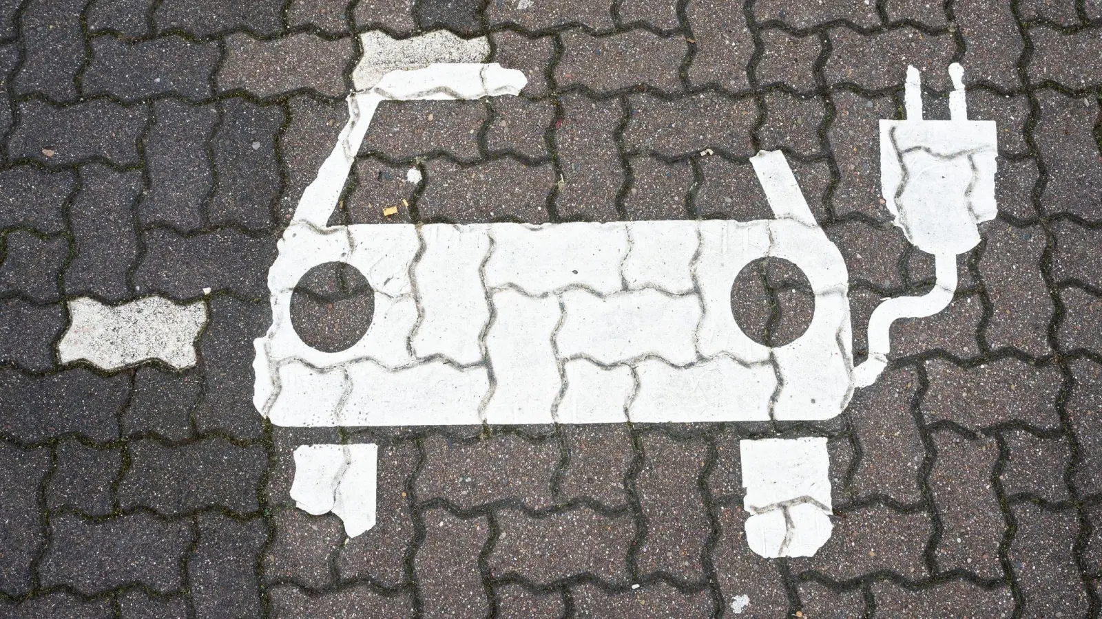 Ein Symbol für E-Autos ist auf einem Parkplatz zu sehen. (Foto: Julian Stratenschulte/dpa/dpa-tmn/Symbolbild)