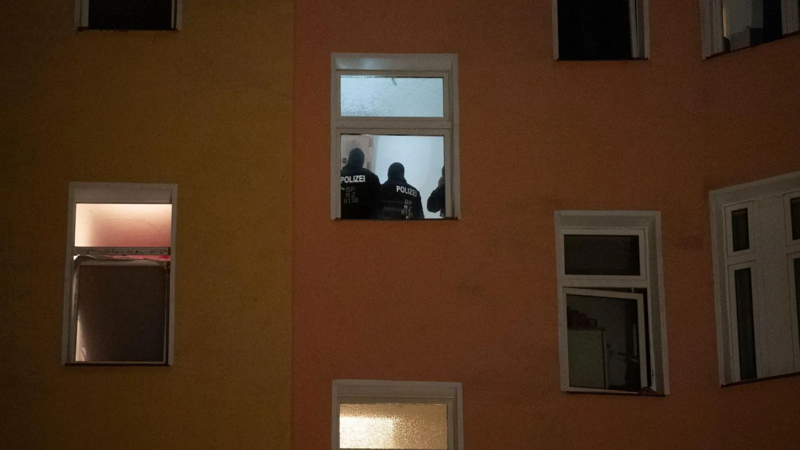 Polizten sind am Morgen im Treppenhaus eines Wohnhauses zu sehen. (Foto: Paul Zinken/dpa)