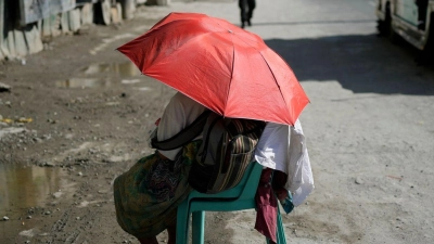 Eine Straßenverkäuferin schützt sich in Manila mit einem Regenschirm vor der Sonne. (Foto: Aaron Favila/AP/dpa)