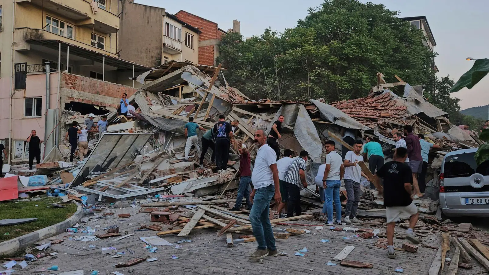 Menschen beseitigen in Sindirgi die Trümmer eines eingestürzten Gebäudes. (Foto: Bahadir Demirceviren/IHA/AP/dpa)