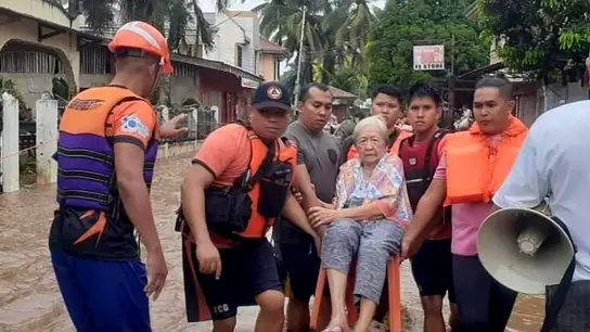 Eine ältere Frau wird von Mitarbeitern der Küstenwache in Sicherheit gebracht. (Foto: Uncredited/Philippine Coast Guard/AP/dpa)