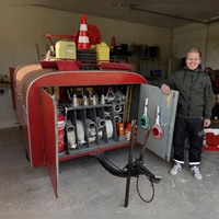 Im seit 1969 bestehenden Feuerwehrhaus ist lediglich Platz für diesen kleinen Spritzenanhänger, den Jens Geuder hier zeigt. Für ein Auto ist das Haus zu klein. Dieser Anhänger wird daher vom ersten Traktor, der nach der Alarmierung eintrifft, zum Brandplatz geschleppt. (Foto: Sylvia Fehlinger)
