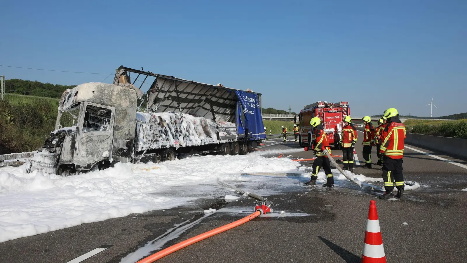 Einsatzkräfte der Feuerwehr richten einen Schlauch auf einen ausgebrannten Lastwagen. (Foto: Ralf Zwiebler/z-media /dpa)