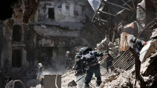 Mitarbeiter des Ministeriums für Notsituationen der selbst ernannten Volksrepublik Donezk räumen Trümmer an der Seite des schwer beschädigten Theatergebäudes. (Foto: Uncredited/AP/dpa)