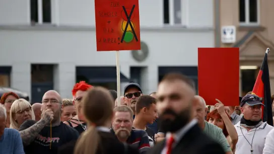 Zuschauer protestieren während der Rede von Bundeskanzler Olaf Scholz bei einer Dialogveranstaltung Bürgern in Neuruppin. (Foto: Carsten Koall/dpa)