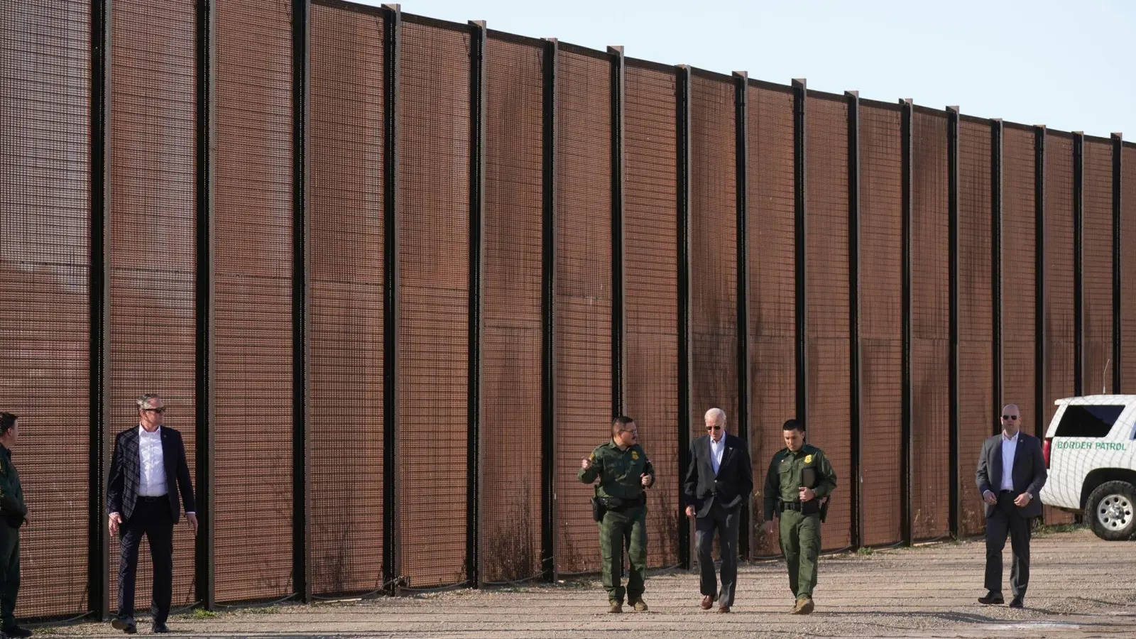 Joe Biden (M), Präsident der USA, besucht die Grenze zwischen den USA und Mexiko und geht mit US-Grenzschutzbeamten entlang eines Abschnitts am Grenzzaun in El Paso, Texas. (Foto: Andrew Harnik/AP/dpa)