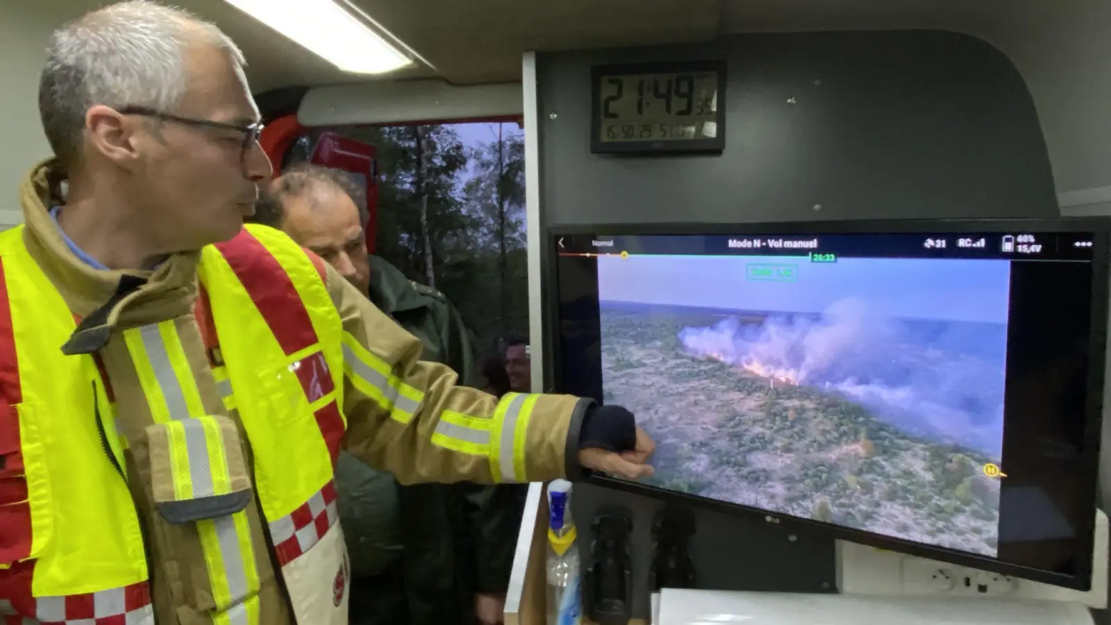 Der Feuerwehrkommandant Francis Cloth (l) zeigt den Moorbrand auf einem Bildschirm. (Foto: Francoise Peiffer/Belga/dpa)