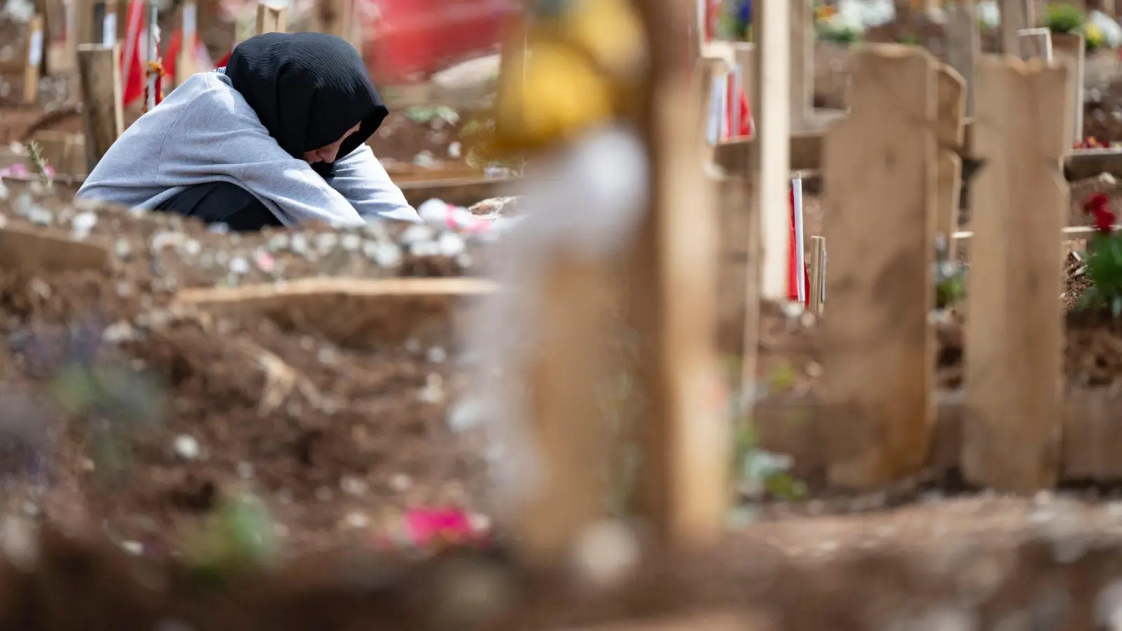 Weinend sitzt eine junge Frau am Grab ihrer Schwestern, die bei dem Erdbeben im Februar ums Leben gekommen waren. (Foto: Boris Roessler/dpa)