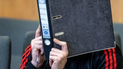 Der Angeklagte verbirgt im Essener Landgericht sein Gesicht hinter einem Aktenordner. (Foto: Christoph Reichwein/dpa)