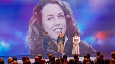 Die Biathletinnen Franziska Preuß und Magdalena Neuner (hier mir Moderator Markus Othmer vor einem Bild von Laura Dahlmeier) haben bei der Verleihung des Bayerischen Sportpreises ihrer gestorbenen Kollegin Dahlmeier gedacht.  (Foto: Alexandra BEIER/BayStMI/dpa)