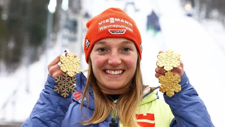 Skispringerin Katharina Althaus zeigt ihr Medaillenset aus Planica, bestehend aus drei Goldmedaillen und einer Bronzemedaille. (Foto: Daniel Karmann/dpa)
