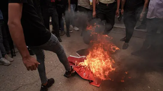 Deonstrierende treten vor dem Konsulat auf eine brennende türkische Flagge. (Foto: Ismael Adnan/dpa)