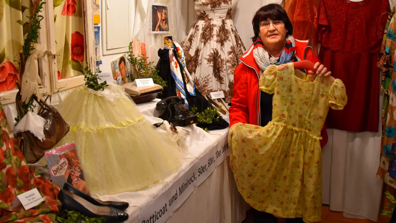 Museumsleiterin Edeltraud Maier hat in vielen Stunden die Ausstellung aufgebaut. Hier legt sie ihr Lieblingsobjekt, ein Kinderkleid aus den 1960er Jahren aus. (Foto: Werner Wenk)