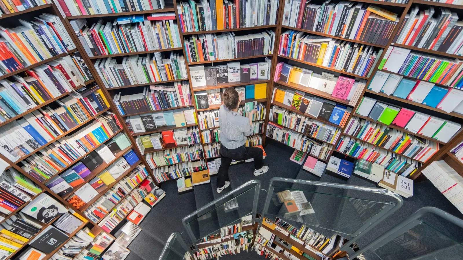 Eine Frau sortiert Bücher in die Regale einer Buchhandlung ein. (Foto: Rolf Vennenbernd/dpa)