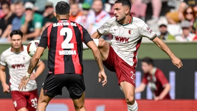 Leverkusens Facundo Medina (links) und Arijon Ibrahimovic vom FC Augsburg kämpfen um den Ball. (Foto: Harry Langer/dpa)