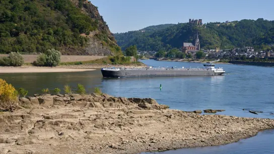 Ein Frachtschiff passiert auf dem Rhein einen Felsen. Durch die anhaltenden Trockenheit des Hochsommers fällt der Wasserspiegel des Mittelrheins immer weiter. (Foto: Thomas Frey/dpa)